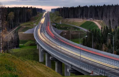 Udsigt fra høj vinkel over lysstriber på vejen mellem træerne